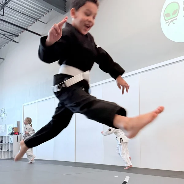 Young Believe Jiu Jitsu student leaping during kids class
